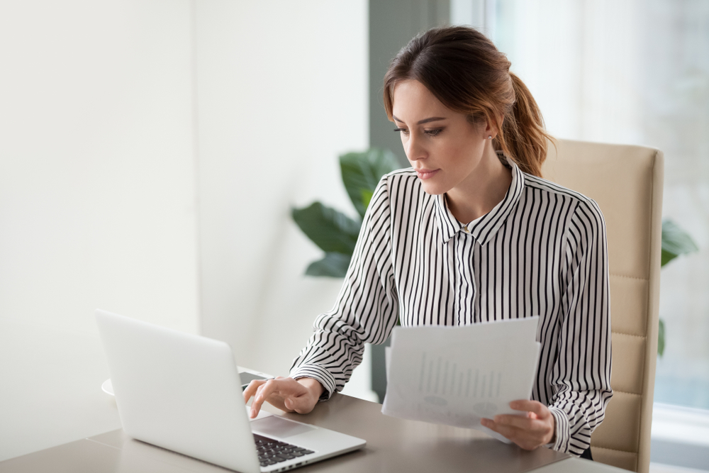 Woman Reviewing Documents in Front of Her Laptop